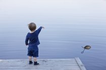 Rear view of boy standing on jetty — Stock Photo