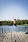 Rear view of boy diving into water from jetty — Stock Photo