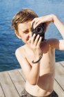 Ritratto di ragazzo che fotografa su pontile, messa a fuoco selettiva — Foto stock