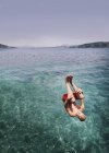 Junger Mann schlägt Purzelbaum ins Meer — Stockfoto