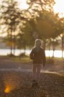 Rückansicht eines Mädchens, das im Park am Fluss spaziert — Stockfoto