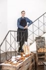 Junge Bäckerin steht auf Treppe mit Bäckerei davor — Stockfoto