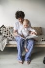 Father reading to baby son at living room — Stock Photo