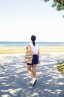 Giovane donna con borsa di tela sulla passerella dalla spiaggia — Foto stock