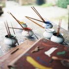 Paintbrushes in small bowls, selective focus — Stock Photo