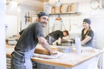 Three bakers making bread in kitchen — Stock Photo