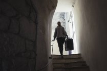 Young woman carrying luggage on staircase — Stock Photo