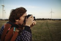 Молодой человек фотографирует поле, фокусируется на переднем плане — стоковое фото
