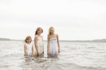 Tres chicas de pie en el agua, enfoque selectivo - foto de stock