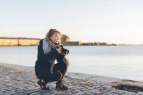 Жінка тримає камеру біля моря, фокус на передньому плані — стокове фото