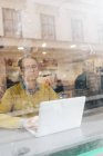 Businessman using laptop behind window, selective focus — Stock Photo