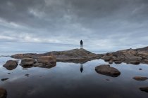 Женщина, стоящая на скалах у озера — стоковое фото