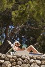 Frau entspannt sich auf Sonnenliege und liest Buch — Stockfoto