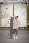 Portrait of boy with skateboard in front of gate — Stock Photo