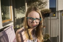 Jeune fille portant des lunettes assis à l'extérieur — Photo de stock