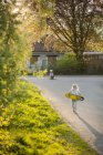 Girl walking to boy with skateboard, selective focus — Stock Photo