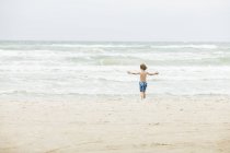 Visão traseira do menino de pé na praia na Dinamarca — Fotografia de Stock