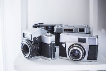 Vintage analogue cameras on white shelf — Stock Photo
