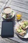 Підвищені вид на сніданок і цифровий планшетний на фоні дерев'яні — стокове фото