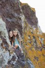 Two young girls looking out of hole in rocks — Stock Photo