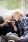 Brothers using smart phone, differential focus — Stock Photo