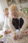 Girl making jigsaw puzzle, focus on foreground — Stock Photo