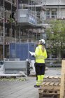 Bauarbeiter mit Bauplänen blickt auf Baustelle — Stockfoto