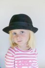 Portrait of girl in black hat looking at camera — Stock Photo