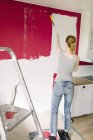 Donna pittura parete in cucina, messa a fuoco selettiva — Foto stock