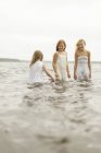 Три девушки, стоящие в воде, дифференциальный фокус — стоковое фото