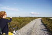 Woman in sunglasses on bike pointing outdoors — Stock Photo