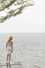 Girl standing on jetty by lake, selective focus — Stock Photo