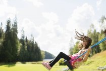 Side view of girl on swing looking at camera — Stock Photo