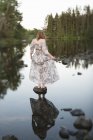 Woman on stone in still water, differential focus — Stock Photo