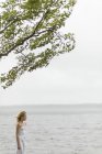 Menina com cabelo loiro em pé junto ao lago — Fotografia de Stock