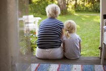 Rear view of woman sitting with girl on porch — Stock Photo