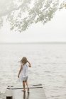 Fille debout sur la jetée par le lac, foyer sélectif — Photo de stock