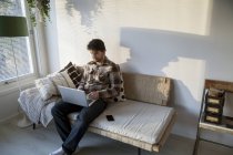 Hombre adulto medio usando el ordenador portátil en la sala de estar - foto de stock
