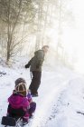 Father pulling two young daughters on sled — Stock Photo