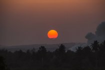 Vista panorámica de la puesta de sol sobre los árboles con humo en Kenia - foto de stock