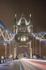 Sendero del semáforo a lo largo de Tower Bridge en la ciudad de Londres por la noche - foto de stock