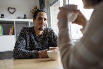 Young couple sitting at table and drinking coffee, selective focus — Stock Photo