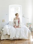 Donna incinta di mezza età seduta sul letto e distogliendo lo sguardo — Foto stock