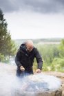 Homme cuisinant sur le feu de camp, foyer sélectif — Photo de stock