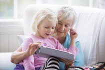 Бабуся і онука дивляться на цифровий планшет — стокове фото