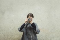 Junge Touristin mit Kamera gegen Wand — Stockfoto
