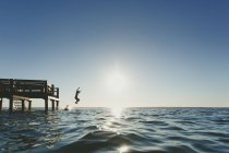 Seitenansicht von zwei Personen, die ins Meer springen — Stockfoto