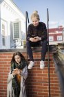 Due giovani donne che utilizzano smartphone sul tetto — Foto stock