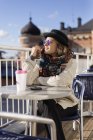 Молода жінка сидить у тротуарному кафе — стокове фото