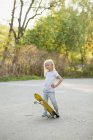 Дівчина позує зі скейтбордом, фокус на передньому плані — стокове фото